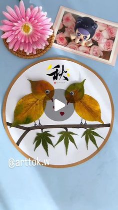 two birds are sitting on a branch with leaves and flowers in front of the plate