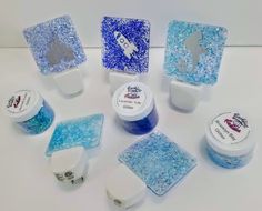 several different colored gels are arranged on a white surface with blue and silver flakes