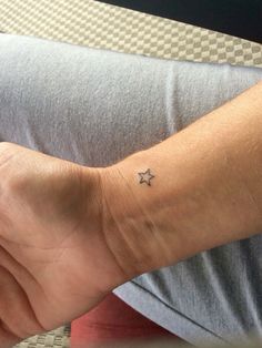 a person with a small star tattoo on their left wrist, sitting down and looking at the camera