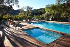 an outdoor swimming pool with lounge chairs and trees in the backgroung area