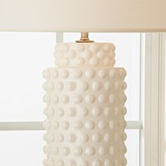 a white lamp sitting on top of a table next to a window