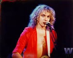 a shirtless man holding a guitar while standing in front of a microphone on stage