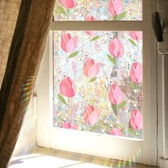 an open window with pink flowers painted on the outside and sun shining in through it