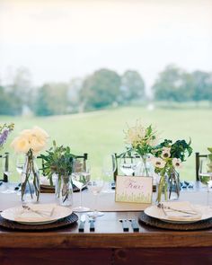 the table is set with place settings and flowers in glass vases on each plate