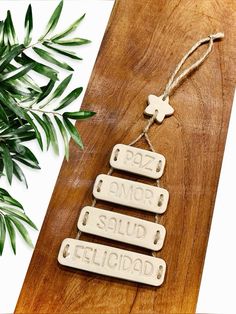 three wooden tags hanging from a string on a wood table next to a potted plant