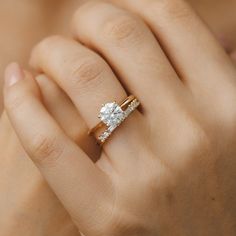 a woman's hand with a diamond ring on top of her finger and an engagement band