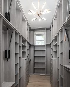 a walk in closet with lots of shelves and lights on the ceiling, along with wooden flooring