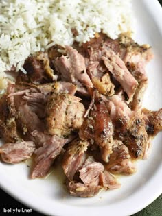 a white plate topped with meat and rice on top of a green table cloth next to a fork