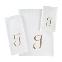 three white towels with gold monogrammed letters