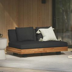 a black couch sitting on top of a wooden floor next to a toilet and window