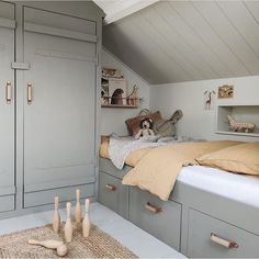 an attic bedroom with gray cabinets and beige bedding, stuffed animals on the floor