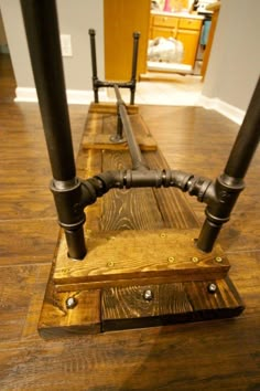 an old wooden bench with pipes attached to the top and bottom, sitting on a hard wood floor