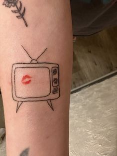 a person with a tattoo on their arm has a red lipstick stain on the tv