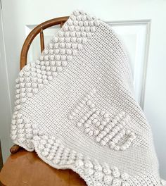 a white crocheted blanket sitting on top of a wooden chair