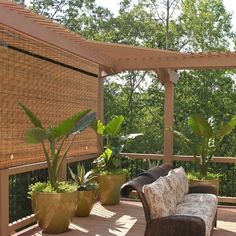 a couch sitting on top of a wooden deck next to two potted planters