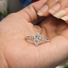 a woman's hand holding an engagement ring with three pear shaped diamonds on it