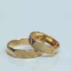 two gold wedding bands with finger prints on them