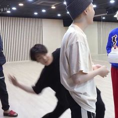 three young men are playing wii bowling in an empty room