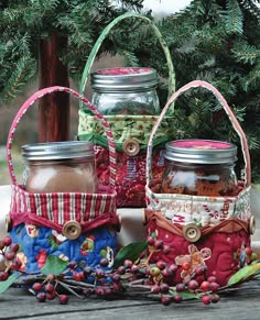 three jars filled with food sitting on top of a wooden table next to pine branches