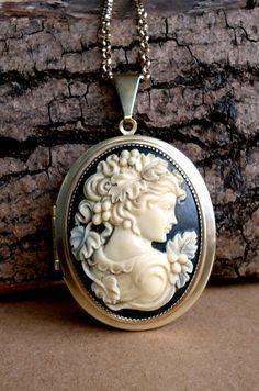 This is a beautiful solid brass (unused) vintage American locket which I have layered with two bezel trays and then adorned with a large 30x40mm Victorian style resin cameo of a lady.  The cameo has been hand painted to bring out the detail and give it an aged appearance. The locket which is raw brass has been polished and sealed with multiple coats of wax.  The locket measures 3.7x5cm with 1.1cm bail and the cameo cabochon is 3x4cm. It is hung from a matching solid brass 3mm belcher chain and finished with a lobster claw clasp. Inside is ample space for photos or keepsakes. Vintage Medallion Cameo Locket Necklace, Vintage Collection Cameo Medallion Locket Necklace, Vintage Collection Medallion Cameo Locket Necklace, Brass Medallion Locket Necklace With Cameo, Antique Brass Cameo Locket Necklace, Antique Gold Cameo Locket Necklace, Antique Gold Locket Necklace With Cameo, Antique Gold Cameo Medallion Locket Necklace, Bronze Oval Cameo Jewelry