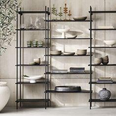 the shelves are filled with dishes and vases in black metal frames, along with other decorative items