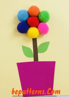 a paper flower with pom - poms in it on a yellow wall background