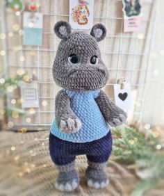 a crocheted hippo is standing in front of a wall with christmas lights