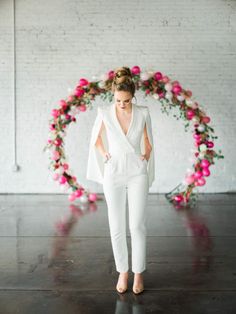 a woman standing in front of a floral wreath