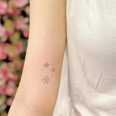 a snowflake tattoo on the arm of a woman with pink flowers in the background