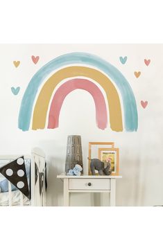 a child's room with a rainbow painted on the wall and hearts around it