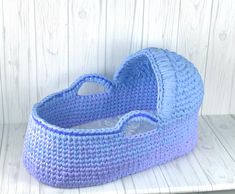 a blue crocheted basket sitting on top of a white wooden shelf next to a wall