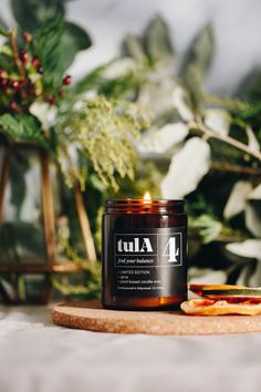 a candle sitting on top of a wooden cutting board next to a potted plant