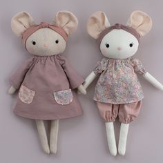 two stuffed animals are dressed in pink and brown outfits, one is holding the other's hand