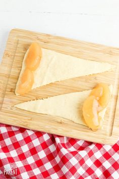 two pieces of bread on a wooden cutting board with a red and white checkered tablecloth