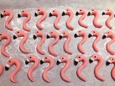 pink flamingos are lined up in rows on a sheet of wax paper with black handles