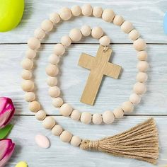 a wooden cross and tassel on a white table with tulips in the background