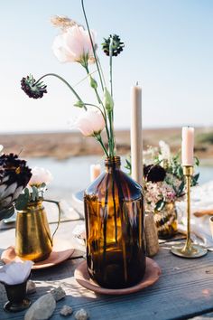 a table topped with vases filled with flowers next to candles and other decor items