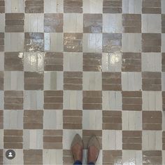 a person standing in front of a tiled wall with their feet up on the floor