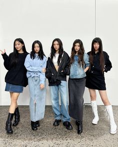 four young women standing next to each other in front of a white wall