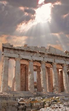 the sun shines through clouds over an ancient temple