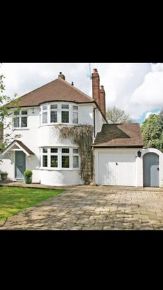 a large white house sitting in the middle of a lush green yard with lots of trees