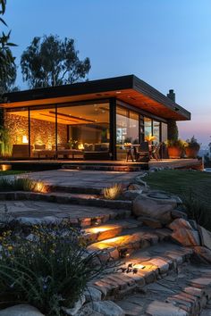 a modern house lit up at night with lights on the windows and steps leading to it