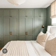 a bedroom with green cabinets and white bedding