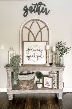 a shelf with some plants and pictures on top of it in front of a sign that says gather