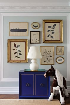 a blue cabinet with pictures on the wall and a horse figurine next to it