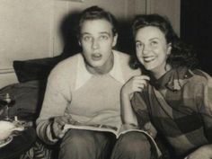 black and white photo of man and woman sitting on the couch reading a book together