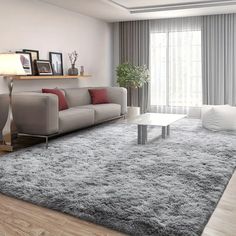 a living room with a couch, coffee table and large rug on the floor in front of a window