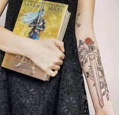 a woman is holding a book in her left hand and tattoos on her right arm