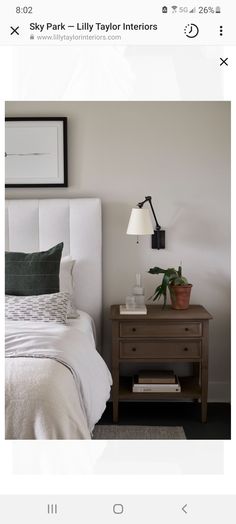 a white bed sitting next to a nightstand with a lamp on it's side