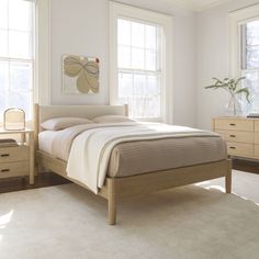 a bed sitting in a bedroom next to two windows and a dresser with drawers on each side